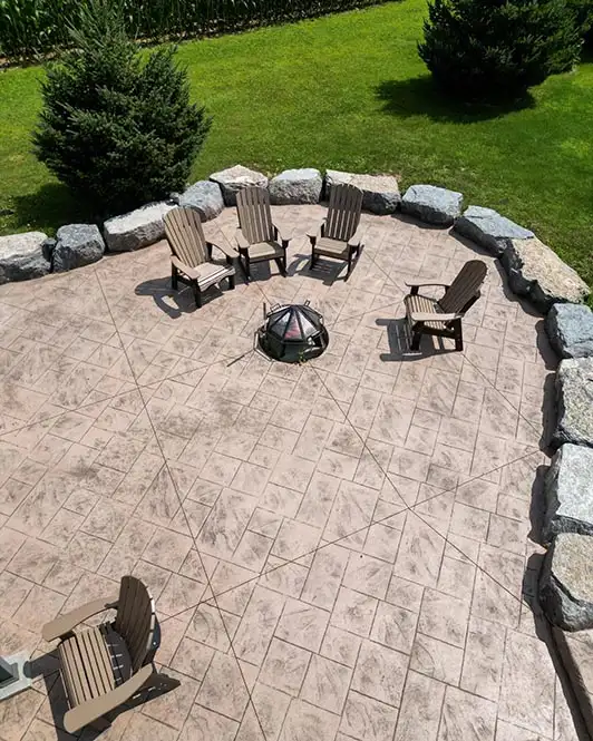 Concrete patio with decorative finish and chairs surrounding a firepit