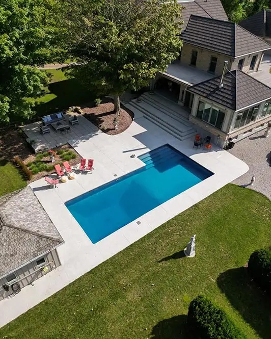 Large backyard with a concrete patio with a pool, lounge area, and pool side chairs