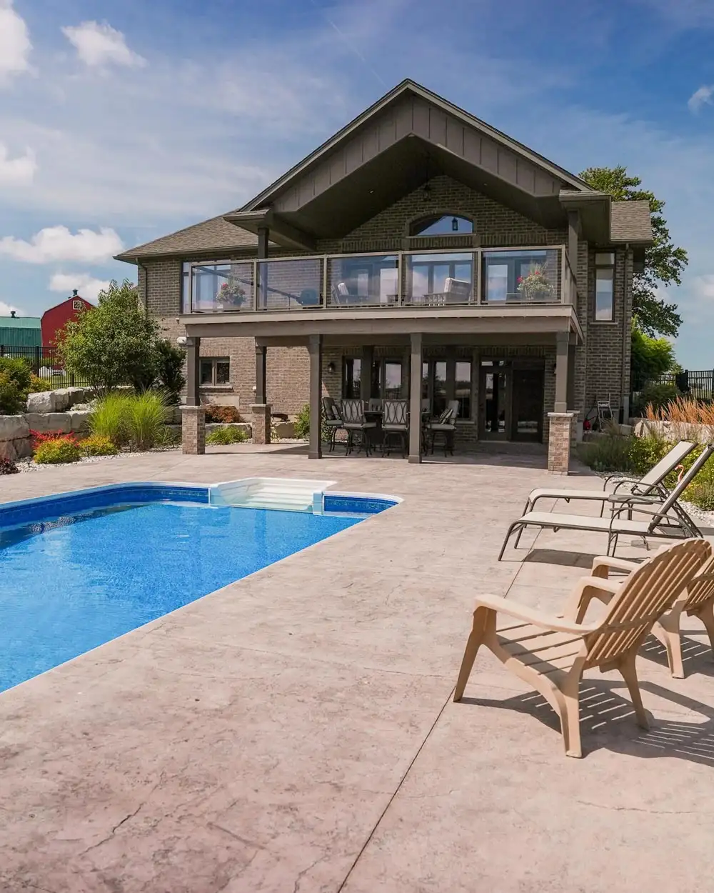 Stamped concrete backyard area with lawn chairs and a built in pool