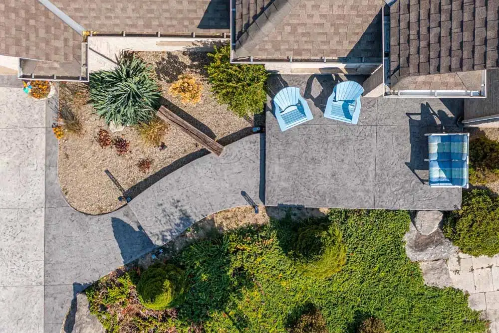 Top-down view of patterned concrete walkway to a house entrance with 4 chairs