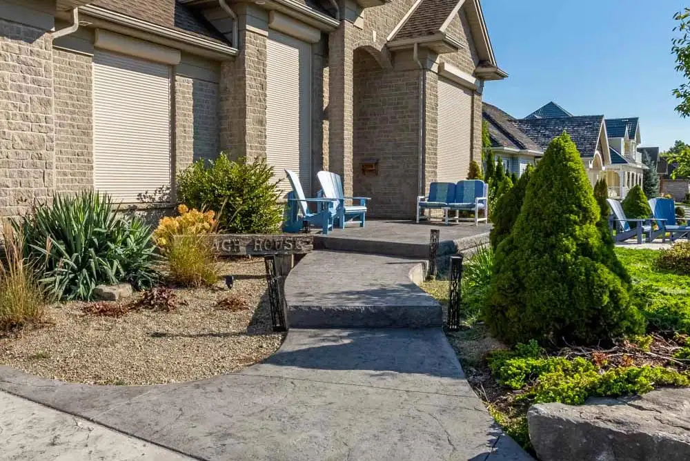 On ground view of patterned concrete walkway to a house entrance with 4 chairs