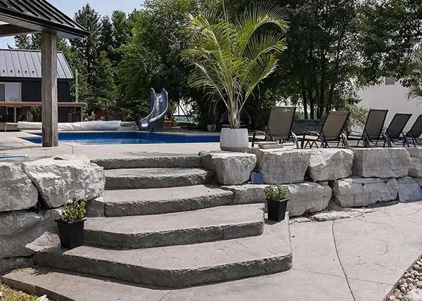 Residential hardscaping and retaining wall by AKKO Ltd with steps leading to a pool