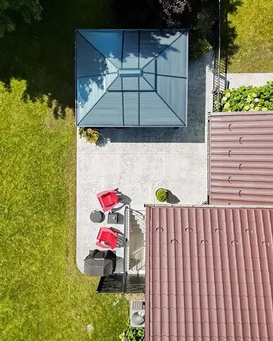 Top-down view of a backyard patio with concrete flooring, bbq area, and a gazebo